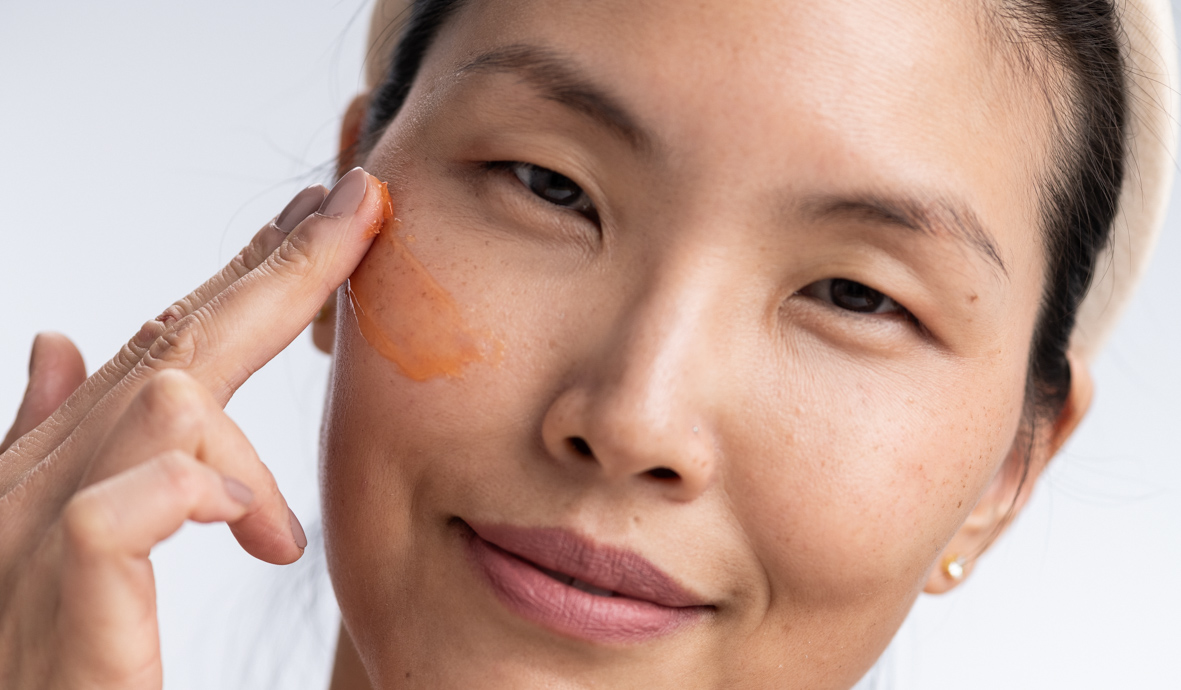 Mulher aplicando produto NUE NUE no rosto — ritual sensorial glass skin